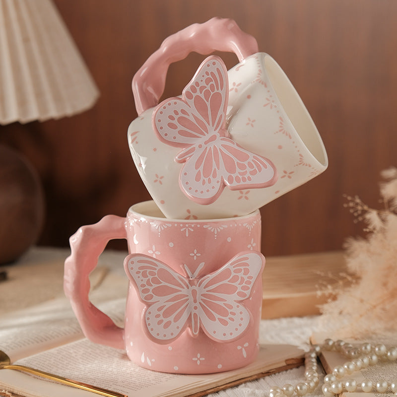 Pink mugs with butterfly designs stacked on a wooden surface.